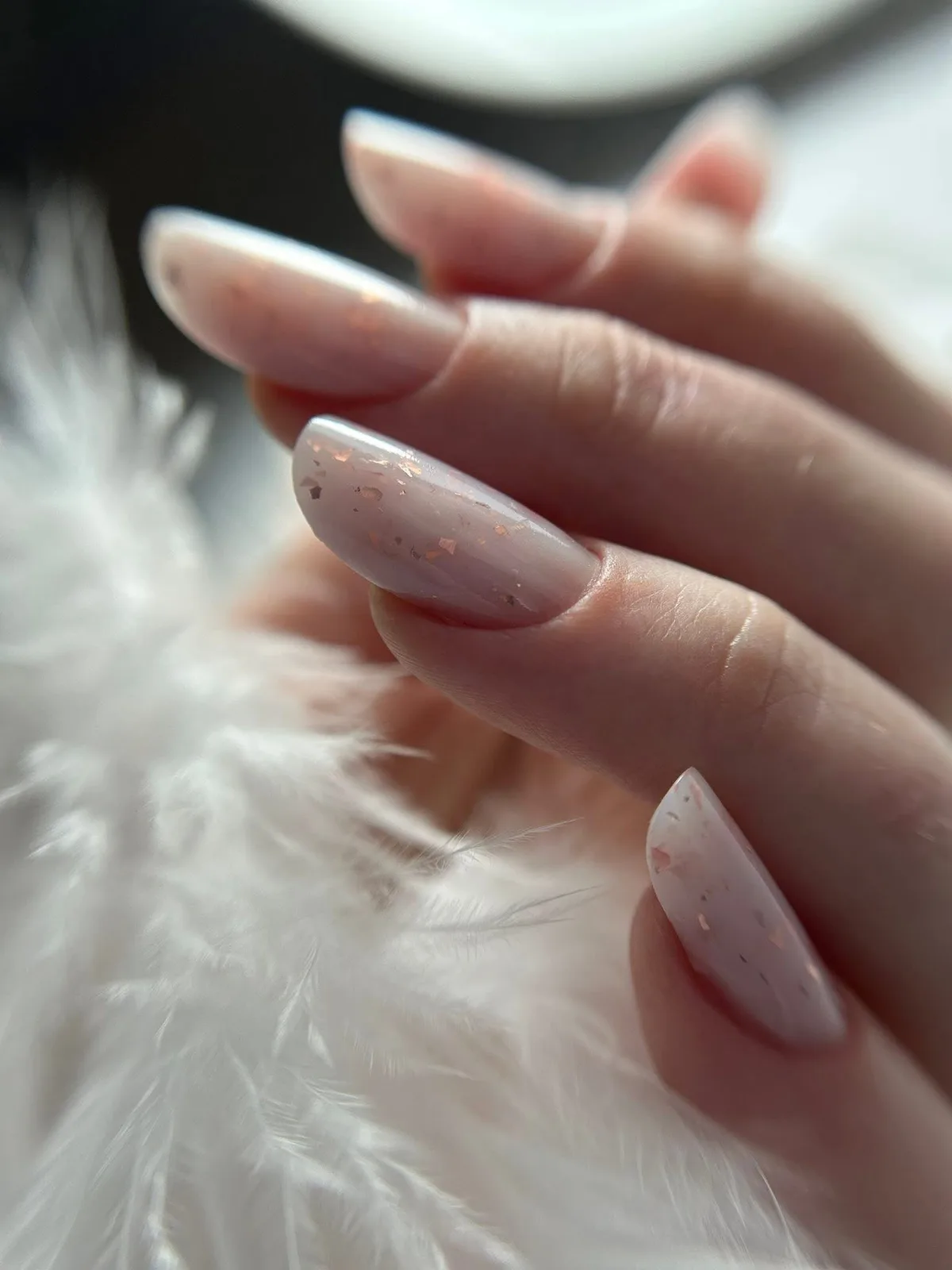 Manichiură în nuanță nude lăptoasă cu particule fine aurii, pe unghii de formă migdalată